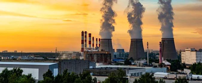 foto de uma industria vista a distancia. Das três torres dela, sai bastante fumaça